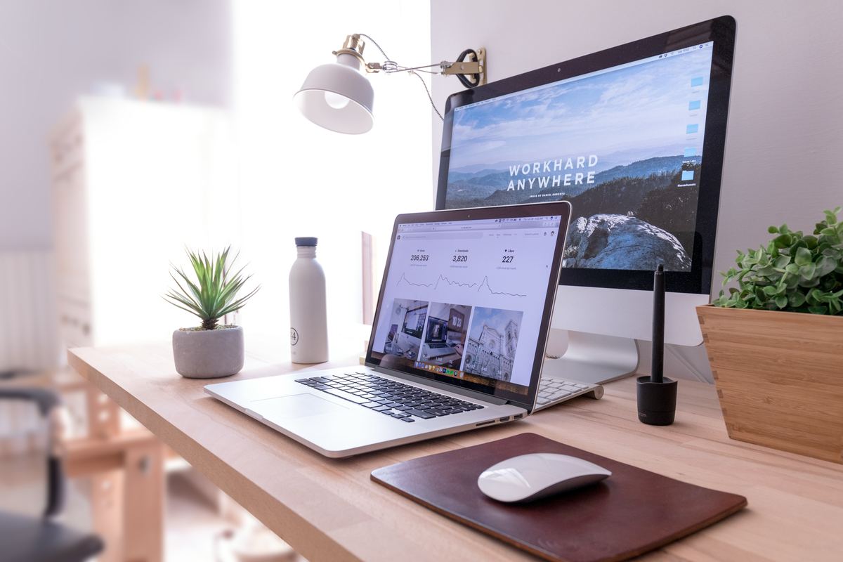 MacBook Pro on a desk beside a white iMac and Magic Mouse